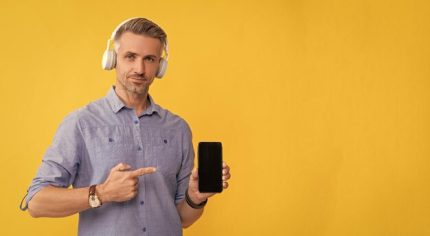 guy-headphones-point-finger-smartphone-man-listen-music-hold-phone